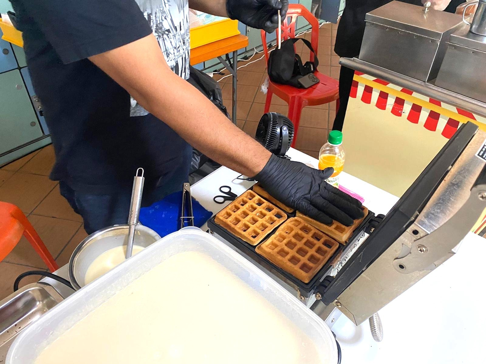 Attendant preparing fresh waffles on an event-station waffle iron