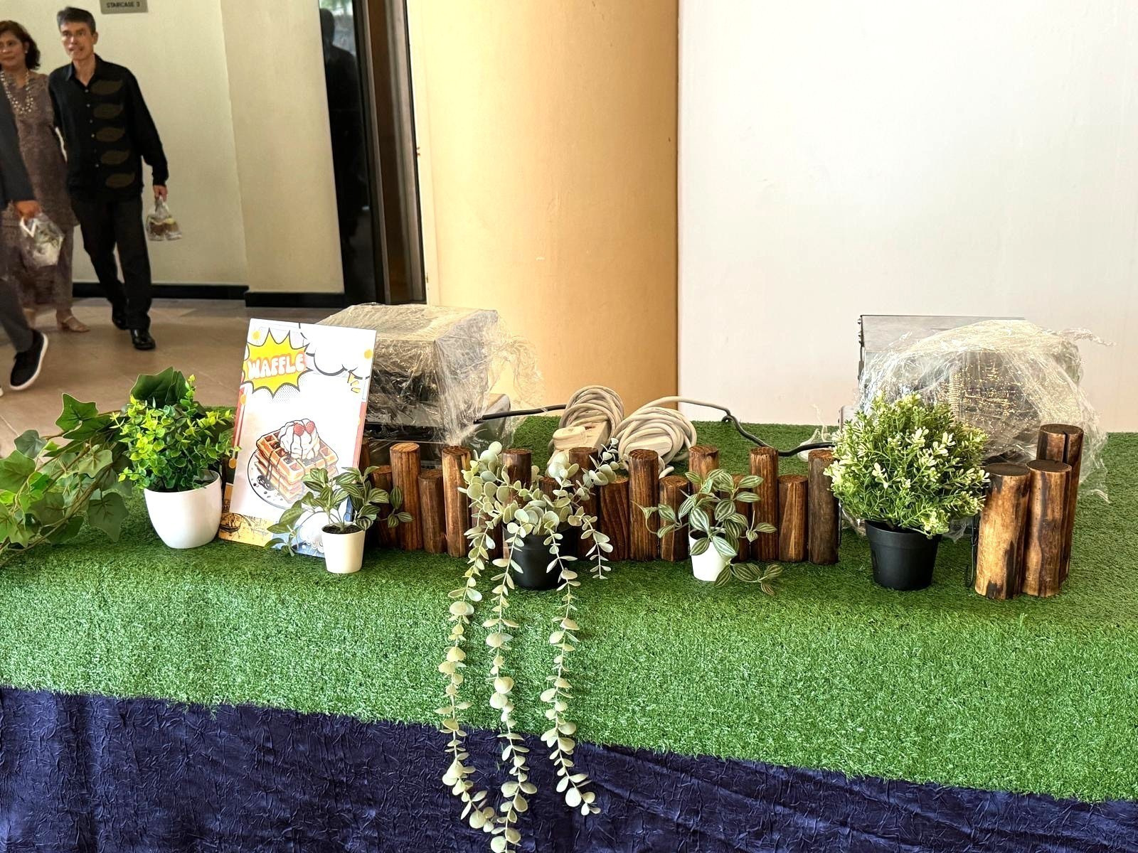 Waffle station with wooden decorations and a grass-covered counter