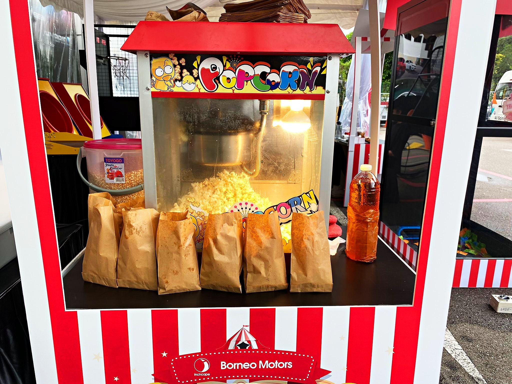 Paper bags of popcorn at a striped event booth