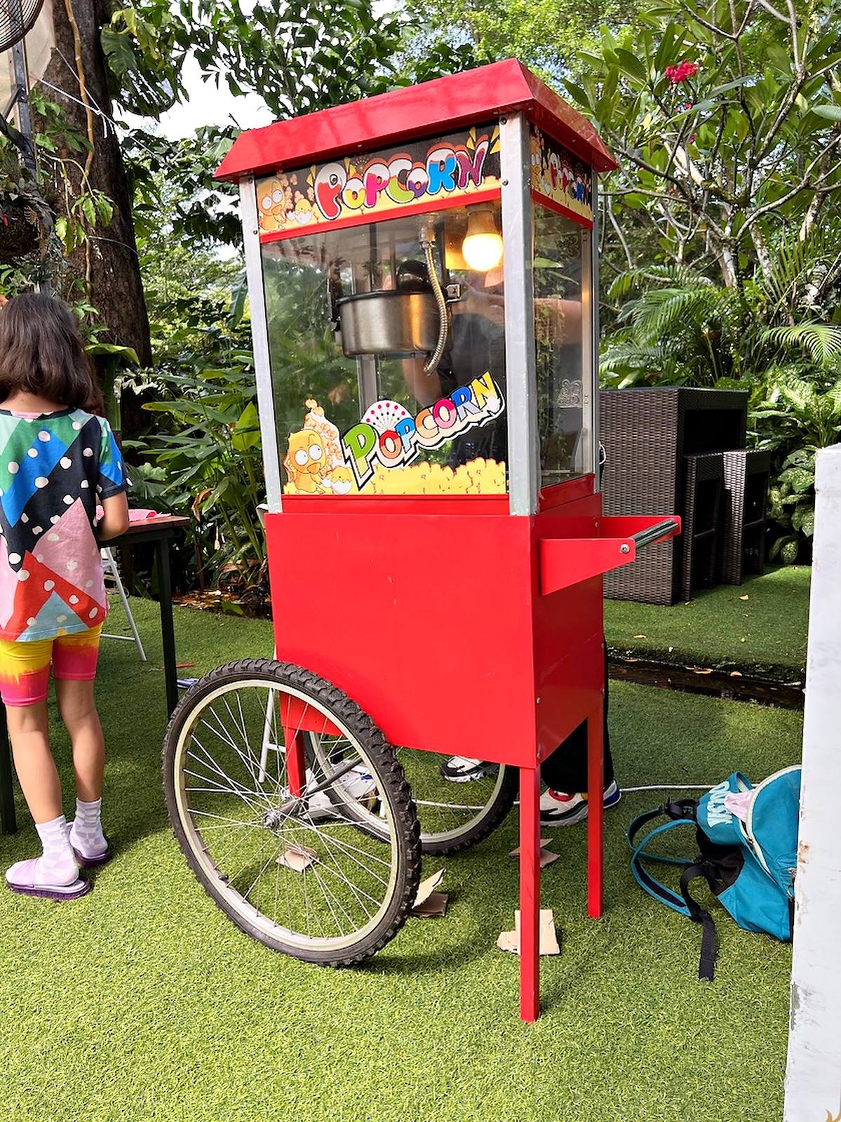 Red popcorn push cart at an outdoor event