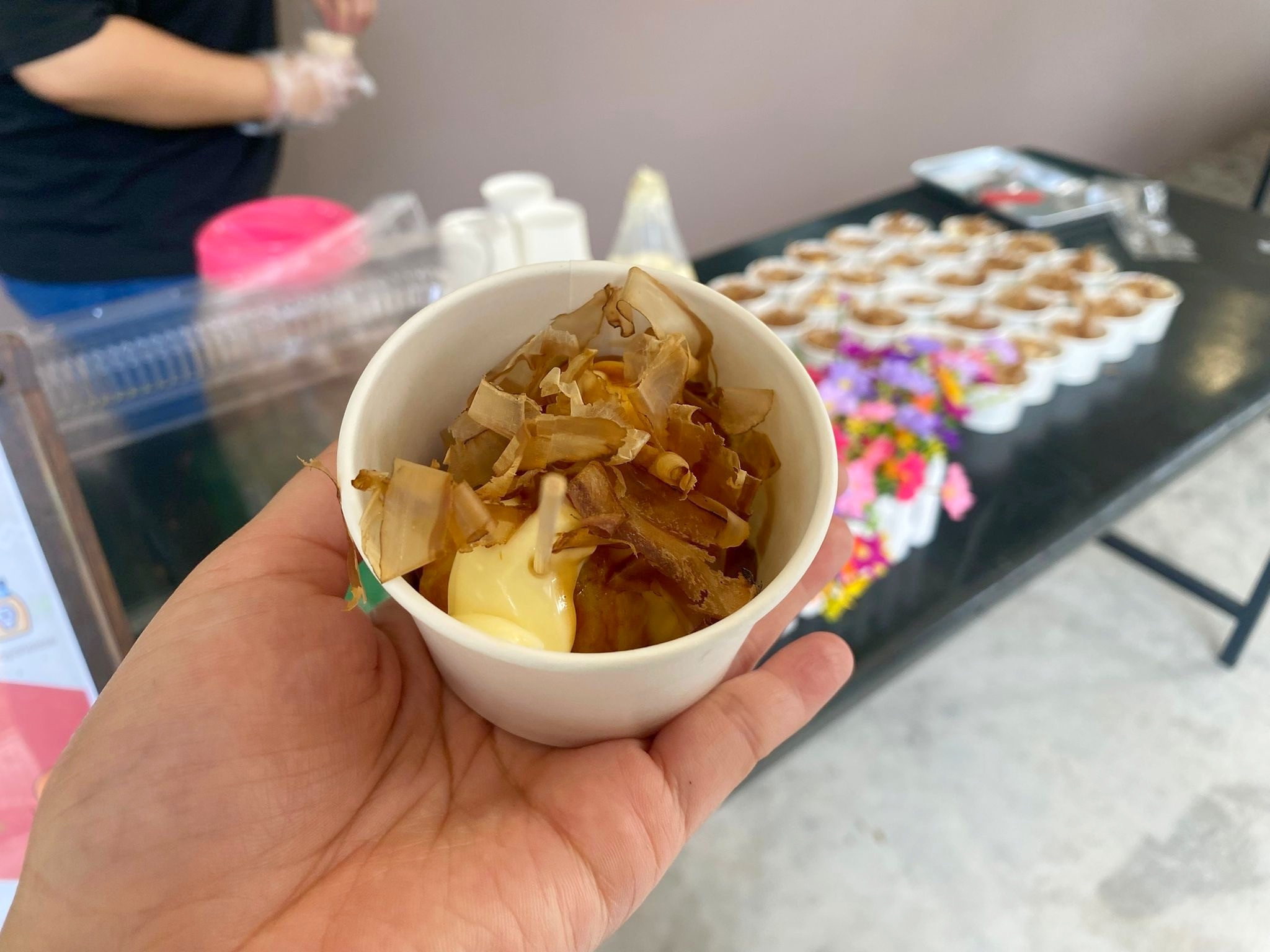 Takoyaki snack cup with sauce and flakes at a serving counter