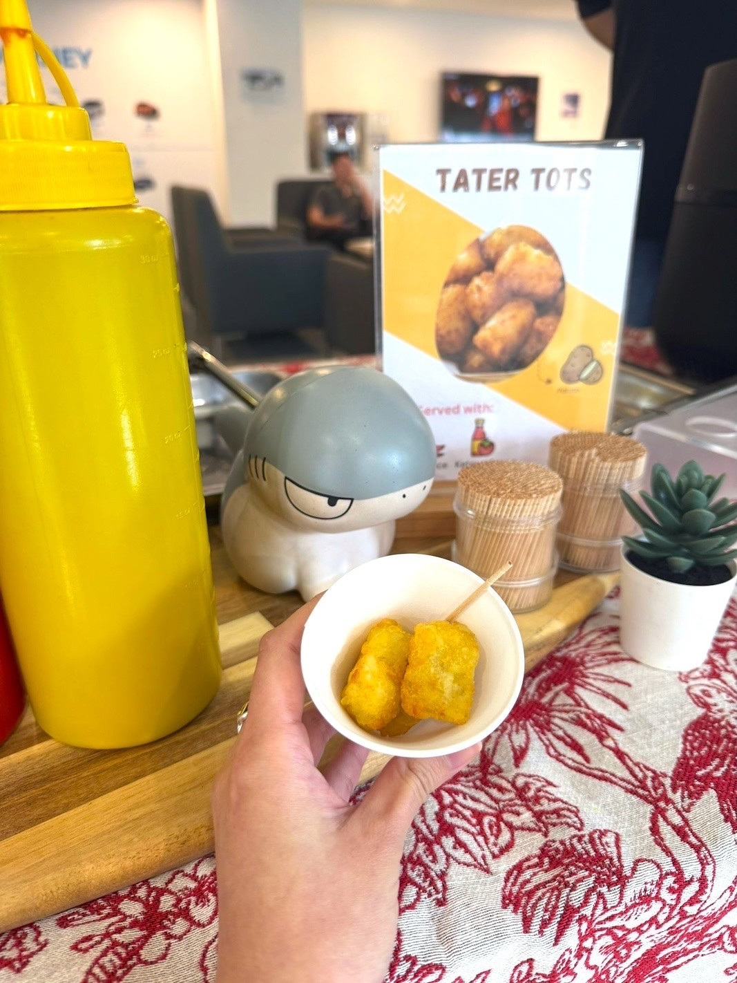 Tater tots in a small paper cup beside the station menu