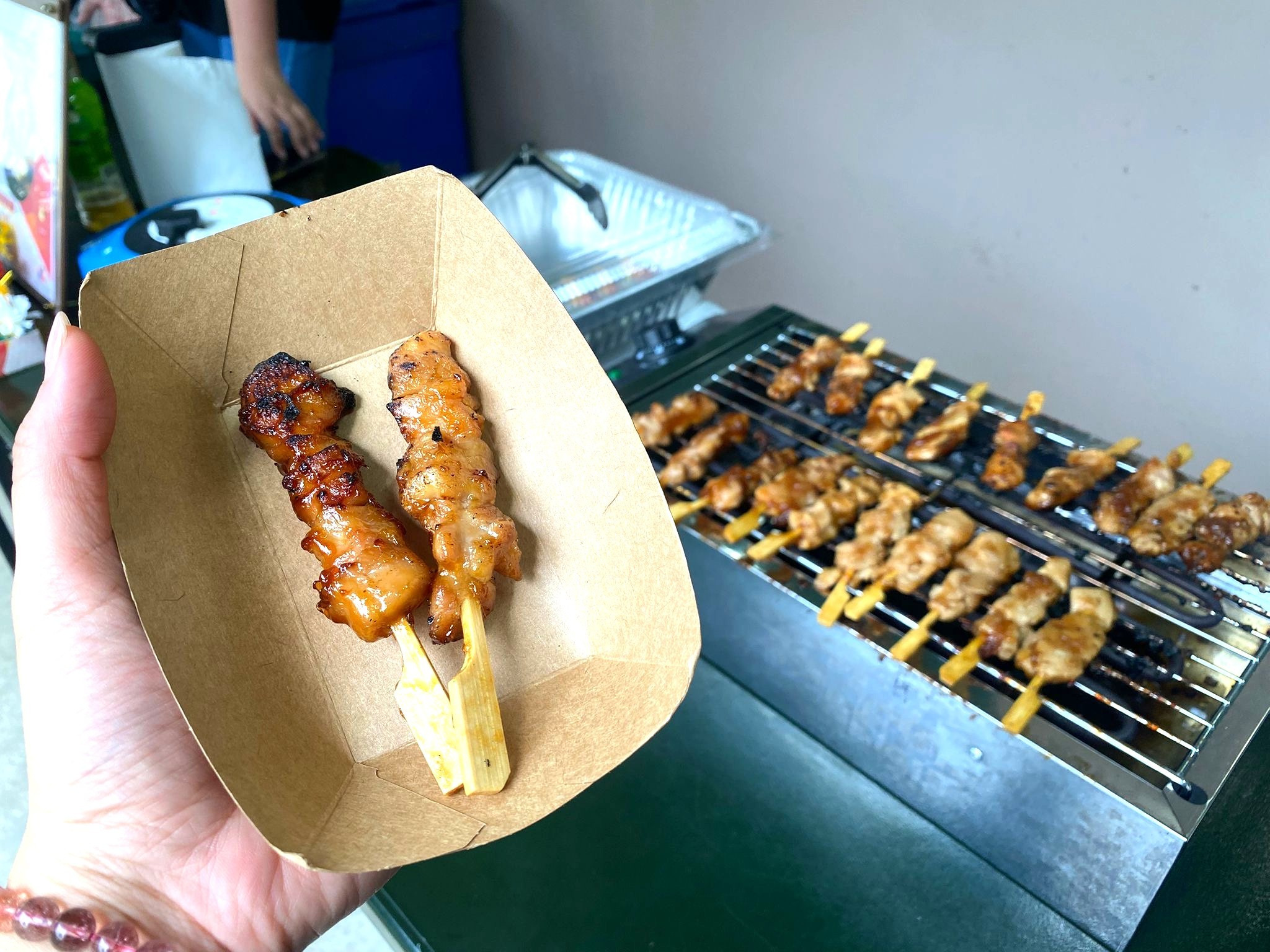 Two yakitori chicken skewers served in a small paper tray