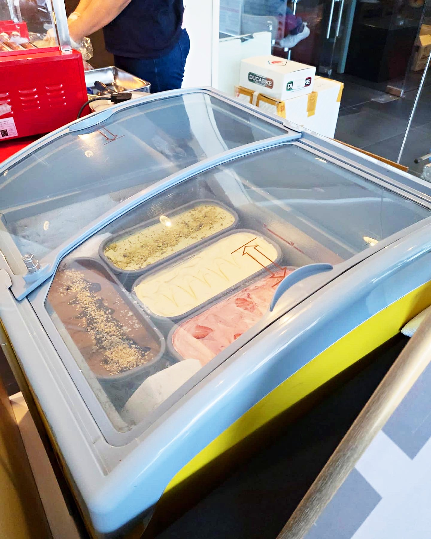 Gelato flavours displayed behind a freezer lid