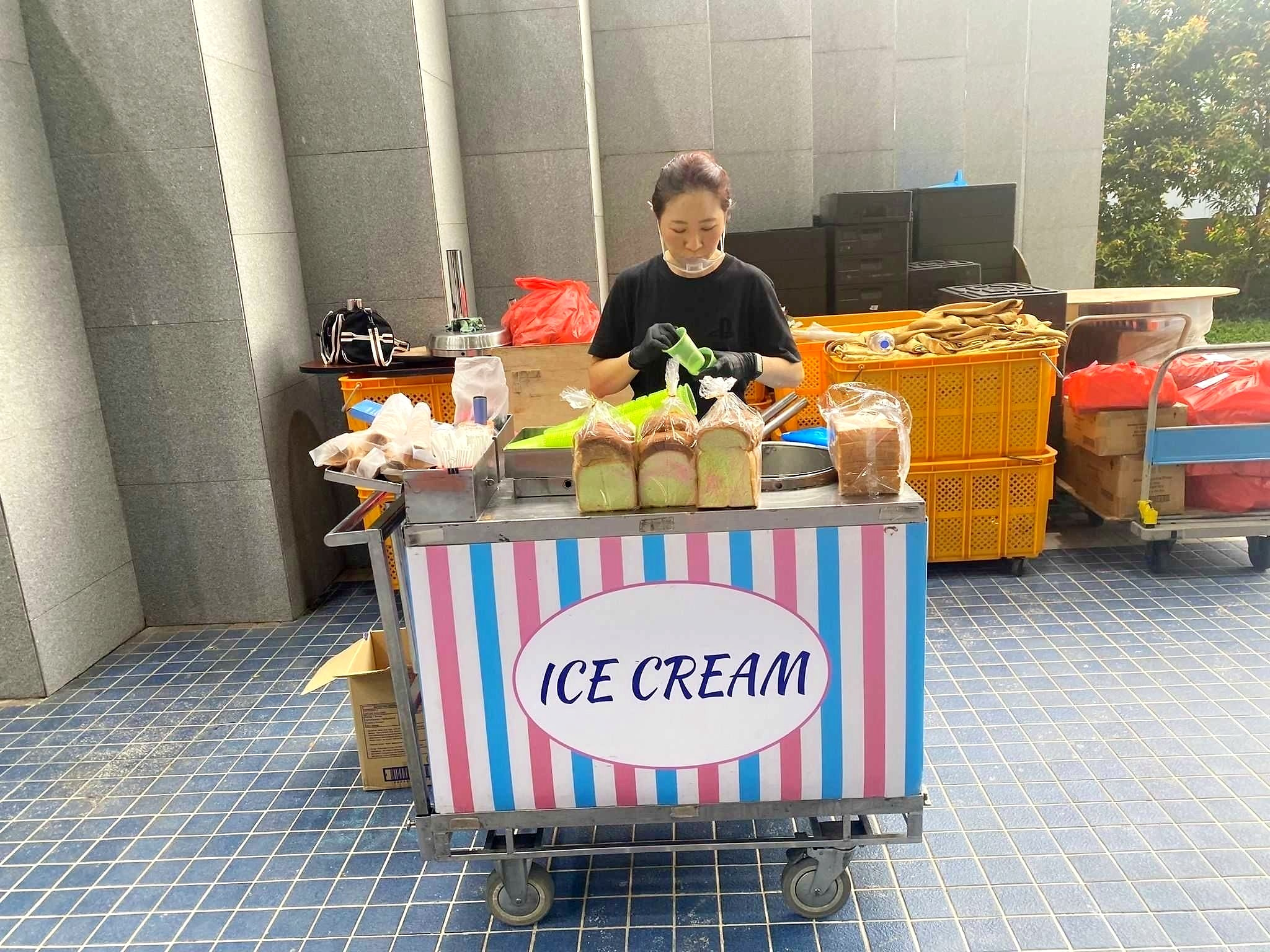 Operator preparing ice cream at a striped outdoor cart